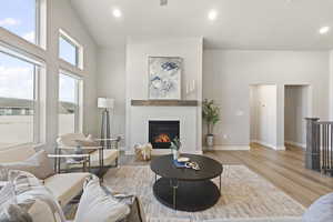 Living area with a fireplace, light wood-type flooring, and recessed lighting