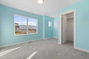 Unfurnished bedroom with a walk in closet and light colored carpet