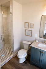 Full bath featuring dark wood finished floors, vanity, and a stall shower
