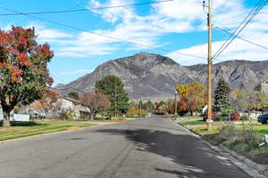 View of asphalt road featuring curbs, a mountain view, and a residential view