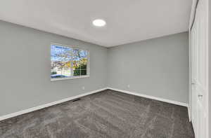 Unfurnished room with dark carpet and baseboards