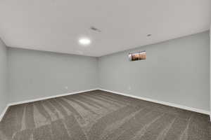 Carpeted spare room featuring baseboards