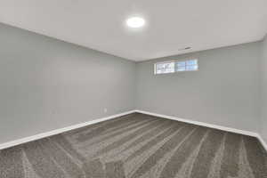 Spare room with dark colored carpet and baseboards