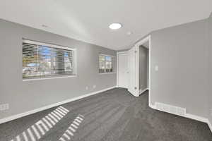 Empty room featuring baseboards and dark colored carpet