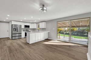 Kitchen with white cabinetry, appliances with stainless steel finishes, recessed lighting, light wood-style floors, and a peninsula
