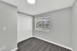 Unfurnished bedroom featuring dark colored carpet and a closet
