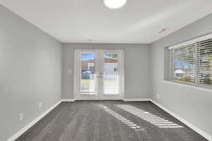 Carpeted spare room with french doors and baseboards