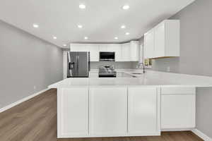 Kitchen featuring a peninsula, white cabinetry, stainless steel appliances, recessed lighting, and light wood-style flooring