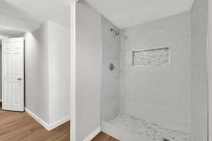 Bathroom featuring a shower stall, wood finished floors, and a textured ceiling