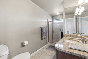 Full bath featuring a shower stall, light tile patterned floors, vanity, and a textured ceiling