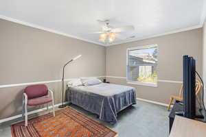 Carpeted bedroom with ornamental molding and a ceiling fan