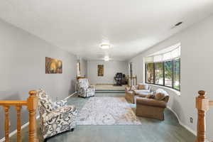 Carpeted living room featuring a desk and baseboards