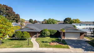 View of front of property featuring a shingled roof, a front lawn, driveway, and a garage