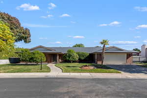 Ranch-style house with a front lawn, brick siding, driveway, a garage, and covered porch
