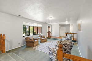 Carpeted living room featuring a textured ceiling and baseboards