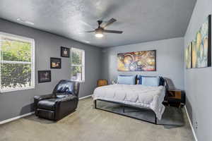 Carpeted bedroom with a textured ceiling and a ceiling fan