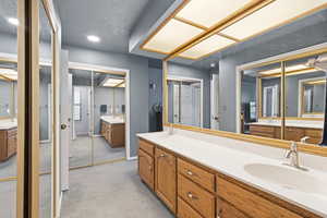 Full bath with double vanity, light colored carpet, a textured ceiling, and recessed lighting