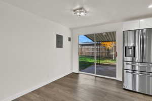 Unfurnished dining area with dark wood-style floors and electric panel