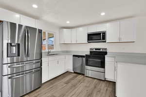 Kitchen featuring stainless steel appliances, white cabinetry, light wood finished floors, and recessed lighting