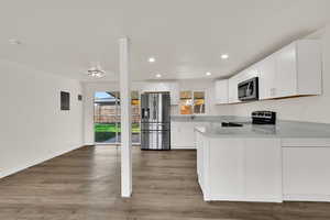 Kitchen featuring white cabinets, appliances with stainless steel finishes, light wood-style flooring, recessed lighting, and a peninsula