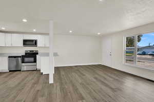 Kitchen with white cabinets, stainless steel appliances, light countertops, light wood-style flooring, and recessed lighting