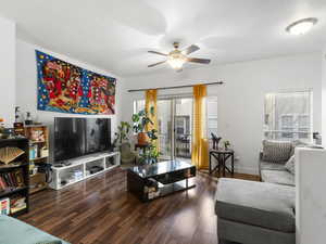 Living room featuring dark wood-style floors and a ceiling fan