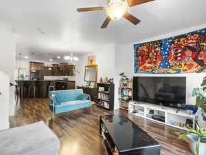 Living room featuring dark wood-type flooring, a ceiling fan, and a chandelier