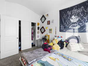 Bedroom with vaulted ceiling, a closet, and carpet flooring