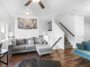 Living area with dark wood-type flooring, stairs, and ceiling fan
