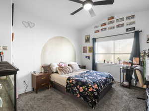 Carpeted bedroom featuring lofted ceiling and a ceiling fan