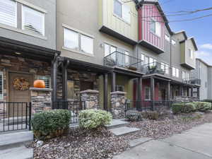 View of front of house with stone siding, stucco siding, board and batten siding, and a balcony