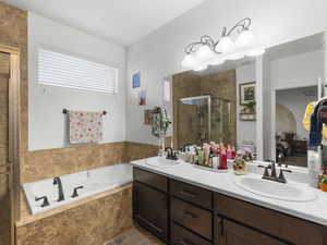 Bathroom featuring a garden tub, double vanity, a stall shower, and ensuite bathroom