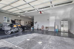 Garage with stainless steel fridge and a garage door opener