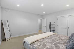 Bedroom featuring recessed lighting, light colored carpet, and a closet