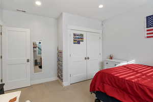 Bedroom with light carpet, recessed lighting, and a closet