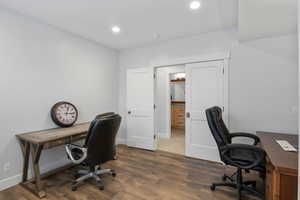 Office space with dark wood-type flooring and recessed lighting