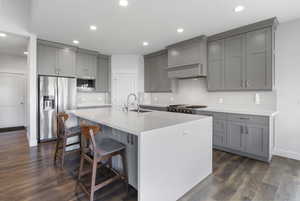 Kitchen featuring gray cabinetry, appliances with stainless steel finishes, tasteful backsplash, a breakfast bar, and recessed lighting