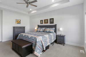 Carpeted bedroom with a tray ceiling, ceiling fan, and recessed lighting