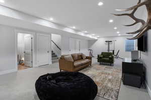 Living room with light carpet, recessed lighting, and stairs