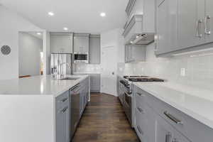 Kitchen featuring gray cabinetry, appliances with stainless steel finishes, backsplash, light stone countertops, and recessed lighting