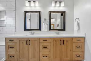 Full bathroom with double vanity and tiled shower