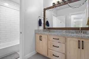 Bathroom with double vanity, light tile patterned floors, and washtub / shower combination