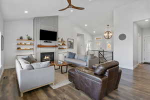 Living area with a chandelier, a large fireplace, dark wood-style floors, recessed lighting, and high vaulted ceiling