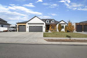 Modern farmhouse featuring concrete driveway, an attached garage, a front yard, and board and batten siding