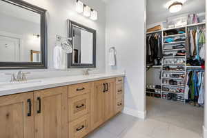 Full bath featuring double vanity, light tile patterned flooring, a walk in closet, and light colored carpet