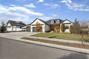 Modern inspired farmhouse with driveway, a front lawn, an attached garage, and board and batten siding
