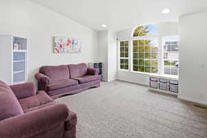 Carpeted living area with vaulted ceiling and recessed lighting