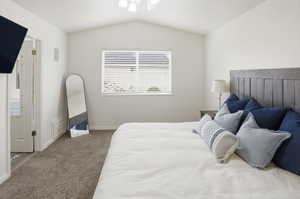 Carpeted bedroom with lofted ceiling and connected bathroom