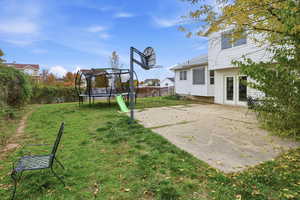 View of yard with a trampoline and a patio
