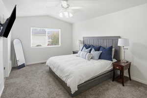 Carpeted bedroom with a ceiling fan and vaulted ceiling